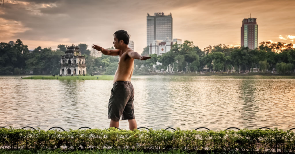 Homme faisant des excercices au bord de l'eau au Vietnam. 